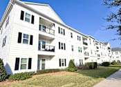 Thumbnail 13 of 28 - A white apartment building with black shutters and balconies.