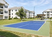 Thumbnail 16 of 22 - A tennis court is surrounded by apartment buildings.
