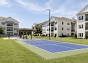 Thumbnail 15 of 22 - A tennis court in front of apartment buildings.