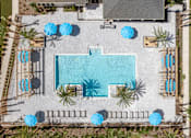 Thumbnail 9 of 28 - An aerial view of a pool surrounded by palm trees and umbrellas.
