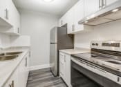 Thumbnail 9 of 16 - Kitchen with white cabinets and stainless steel appliances at Platts Crossing, London, ON