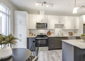 Thumbnail 17 of 28 - Kitchen with white cabinets and black appliances and a table and chairs  at 101 Base Line Road West, Ontario