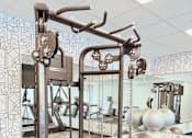 Thumbnail 8 of 37 - A gym with a weight machine in the foreground.