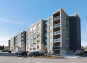 Thumbnail 1 of 11 - a large apartment building with a parking lot in front of it