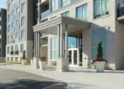 Thumbnail 2 of 11 - an entrance to an apartment building with potted plants on the sidewalk