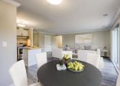 Thumbnail 4 of 23 - a dining area with a table and chairs and a kitchen in the background