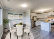 Thumbnail 3 of 23 - a dining area with a table and chairs and a kitchen in the background