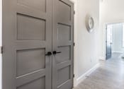 Thumbnail 31 of 37 - A grey double door with a black handle and a round clock on the wall.