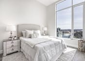 Thumbnail 24 of 37 - A bedroom with a large bed and a view of the city.