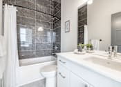 Thumbnail 32 of 37 - A white bathroom with a marble tile wall and a white toilet.