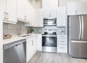 Thumbnail 17 of 37 - A modern kitchen with white cabinets and stainless steel appliances.