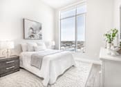 Thumbnail 28 of 37 - A bedroom with a large bed and a view of the city.