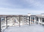 Thumbnail 37 of 37 - A view from a balcony overlooking a parking lot and buildings.