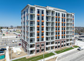 Thumbnail 3 of 37 - A large multi-story building with a parking lot in front.