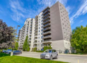 Thumbnail 19 of 23 - a large apartment building with cars parked in front of it