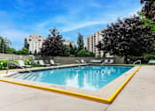 Thumbnail 3 of 10 - A swimming pool surrounded by trees and chairs.