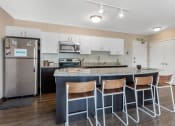 Thumbnail 38 of 42 - a kitchen with an island with bar stools and a stainless steel refrigerator