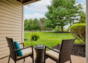 Thumbnail 7 of 11 - A patio with two chairs and a table with a plant in the background.