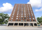 Thumbnail 3 of 43 - a tall building with many windows and a cloudy blue sky in the background
