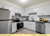 Thumbnail 20 of 24 - A kitchen with white cabinets and a black fridge.