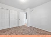 Thumbnail 26 of 35 - A bedroom with a carpeted floor and two doors.