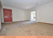 Thumbnail 10 of 24 - A living room with a red door and carpeted floor.