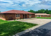 Thumbnail 2 of 14 - A red brick building with a green lawn in front.
