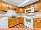Thumbnail 16 of 35 - A kitchen with wooden cabinets and white appliances.