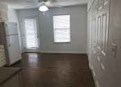 Thumbnail 28 of 51 - A kitchen with a refrigerator, wooden floors, and white walls.