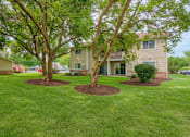 Thumbnail 6 of 11 - A house with a green lawn and two trees in front.