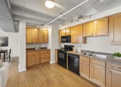 Thumbnail 23 of 43 - a kitchen with wooden cabinets and appliances and a living room with a table and chairs