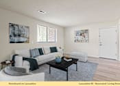 Thumbnail 12 of 24 - A living room with a grey couch, a coffee table, and two chairs.
