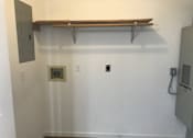 Thumbnail 30 of 51 - A white wall with a brown shelf and a grey electrical box.