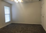 Thumbnail 20 of 51 - A room with a carpeted floor, a ceiling fan, and a window with blinds.