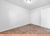 Thumbnail 32 of 35 - A bedroom with a carpeted floor and two doors.