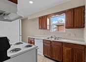 Thumbnail 12 of 14 - A kitchen with a white stove and brown cabinets.