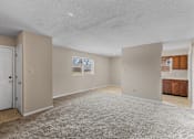 Thumbnail 6 of 14 - A spacious room with a carpeted floor and a door on the left side.
