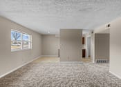 Thumbnail 7 of 14 - A spacious room with beige carpeting and a window overlooking a street.