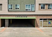 Thumbnail 8 of 56 - A parking garage entrance with a green sign above it.