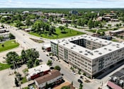 Thumbnail 4 of 56 - A large grey building is surrounded by smaller buildings and trees.