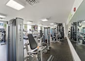 Thumbnail 28 of 56 - A gym with a variety of equipment including a treadmill.
