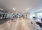 Thumbnail 12 of 38 - A spacious gym with a variety of equipment and a dining table.