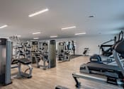 Thumbnail 11 of 38 - A gym with a variety of equipment including treadmills, weights, and exercise machines.