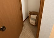Thumbnail 13 of 13 - A small room with a door, a basket, and a plant.