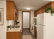 Thumbnail 9 of 13 - A kitchen with a white refrigerator and wooden cabinets.