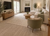 Thumbnail 7 of 13 - A living room with a grey armchair, a white sofa, a wooden coffee table, a flat screen TV, and a fireplace.