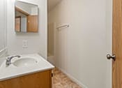 Thumbnail 28 of 64 - A bathroom with a sink, mirror, and wooden door.