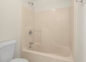 Thumbnail 37 of 64 - A white toilet sits next to a white bathtub in a bathroom.