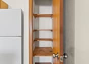 Thumbnail 25 of 64 - A white refrigerator is next to a wooden door with shelves.