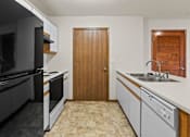 Thumbnail 54 of 64 - A kitchen with a black refrigerator, white cabinets, and a wooden door.